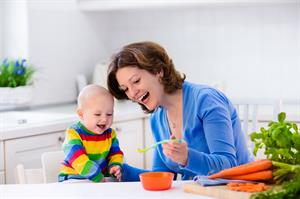 Frau füttert Baby am Tisch